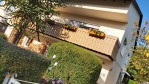 A two-story building with a balcony, a well-maintained hedge, and flower boxes.