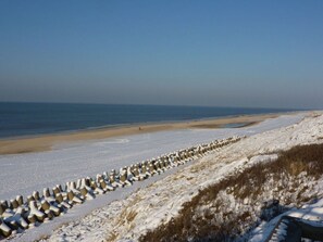 A snow-covered beach with a row of concrete sea defenses. - Maiken Feikes, \"am Friedrichshain\" 2 (Sylt)