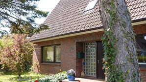 Une maison en briques avec un toit en tuiles, une fenêtre et une porte avec des panneaux de verre.