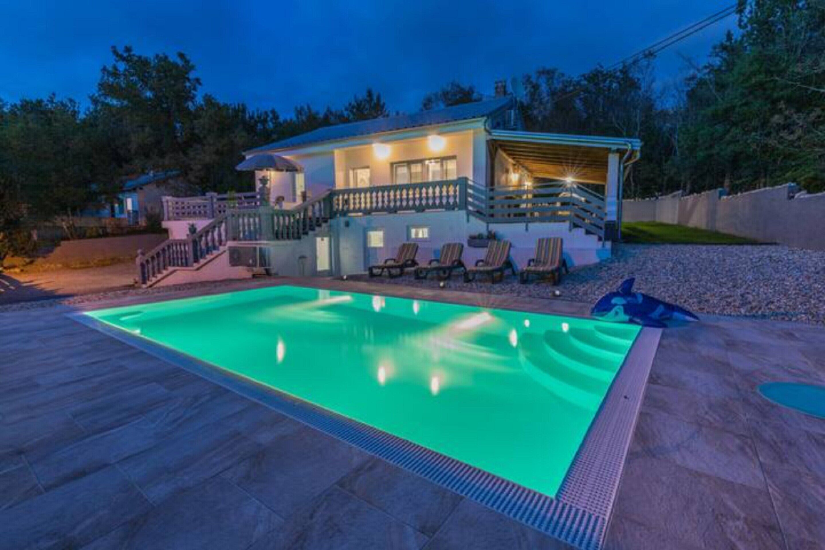 Ein zweistöckiges Haus mit Swimmingpool und Sitzbereich im Freien.