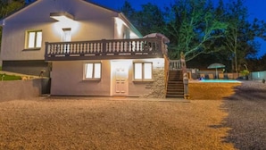A modern two-story house with a stone entrance, a covered porch, and a swimming pool in the background. - Apartment in Croatia Near the Adriatic Coast (Vinodol)