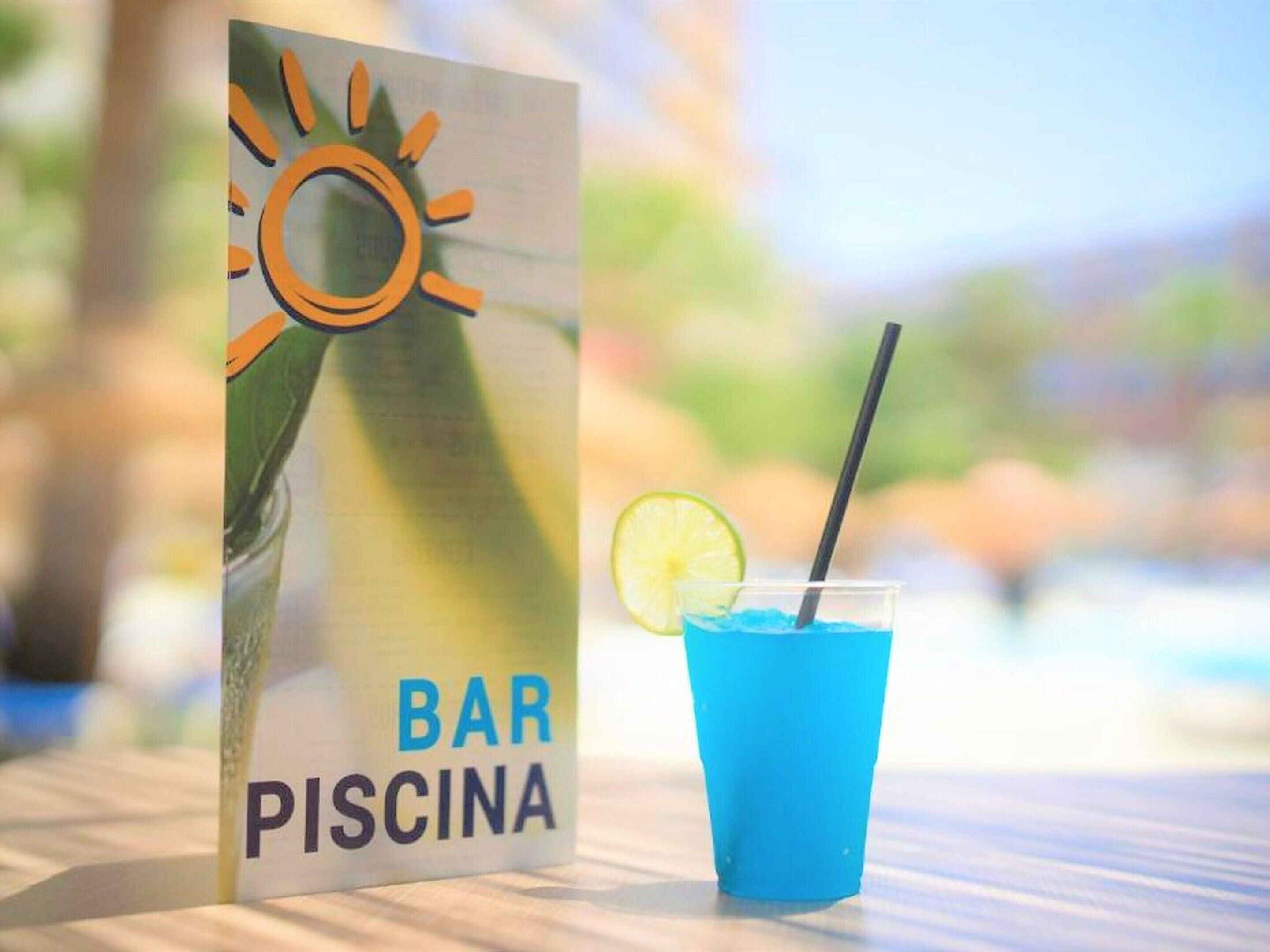 A bar sign with a sun and pool icon, a blue drink with a straw and lime slice, and a blurred outdoor background.