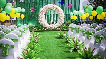 A wedding aisle with white chairs, a green carpet, and a floral arch.