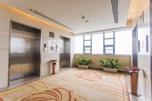 An elevator area with two elevators, a patterned carpet, and potted plants. - Minsheng Hotel (Yichang)