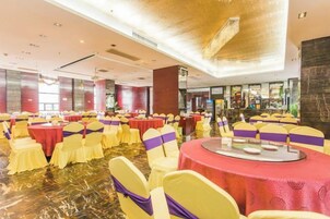 Un salón de banquetes con mesas y sillas redondas, piso pulido y un diseño moderno del techo.