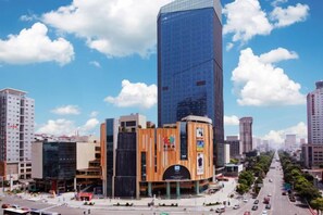 A modern urban area with a prominent skyscraper, a round building with a central atrium, and a busy street with vehicles and pedestrians. - Minsheng Hotel (Yichang)