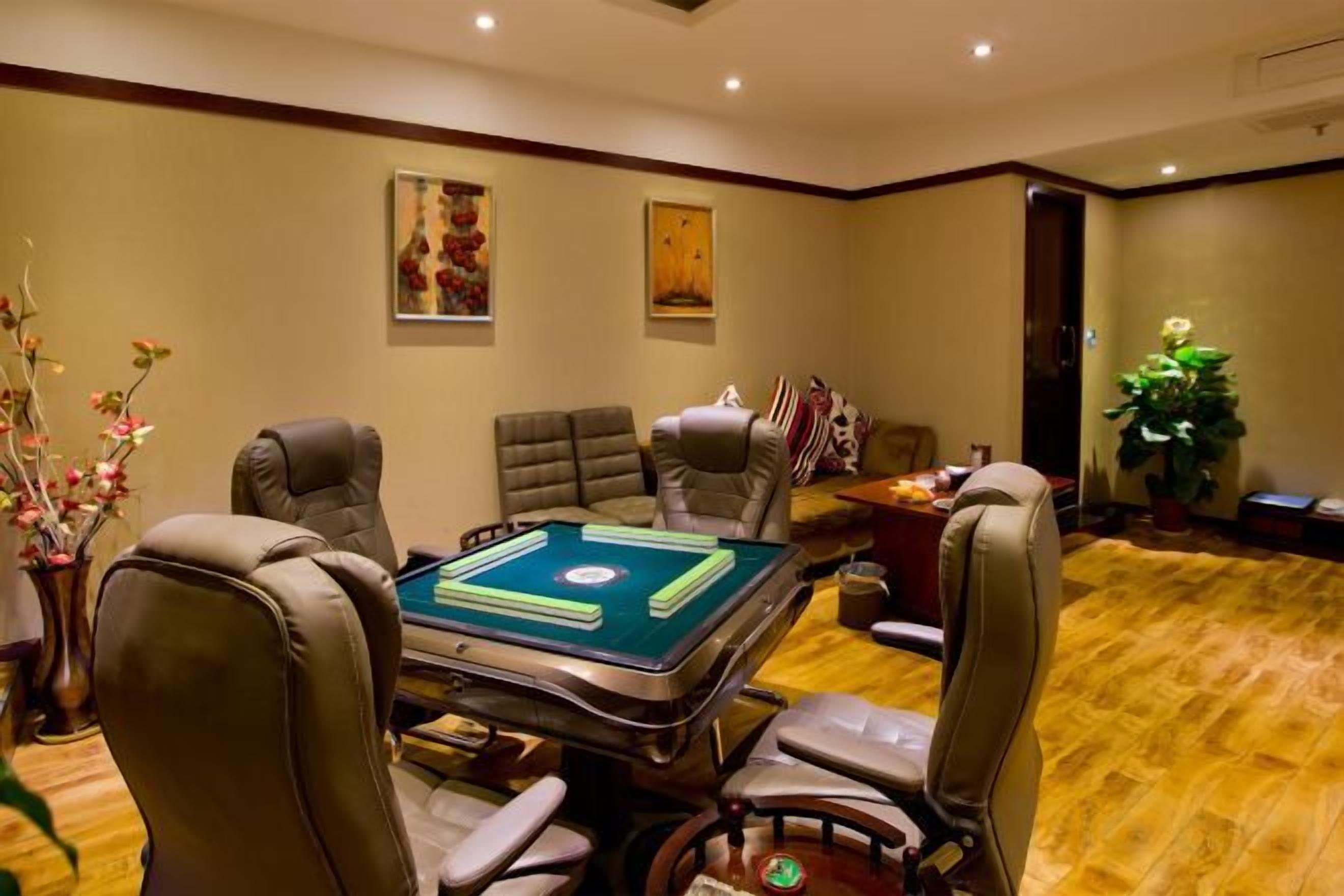 Una habitación con mesa de billar, sillones de cuero y piso alfombrado.