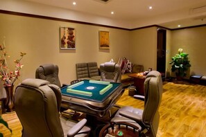 Une pièce avec une table de billard, des fauteuils en cuir et un sol recouvert de moquette.
