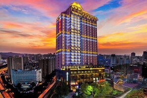 A high-rise hotel with multiple floors, surrounded by other buildings, and a cityscape in the background. - Minsheng Hotel (Yichang)