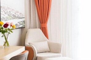 A modern room with a white armchair, a wooden table, a vase with flowers, and a painting on the wall. - Minsheng Hotel (Yichang)