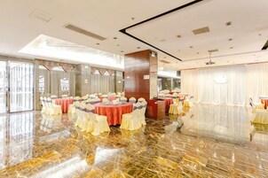 Un salón de banquetes con mesas redondas, sillas y un suelo de mármol pulido.