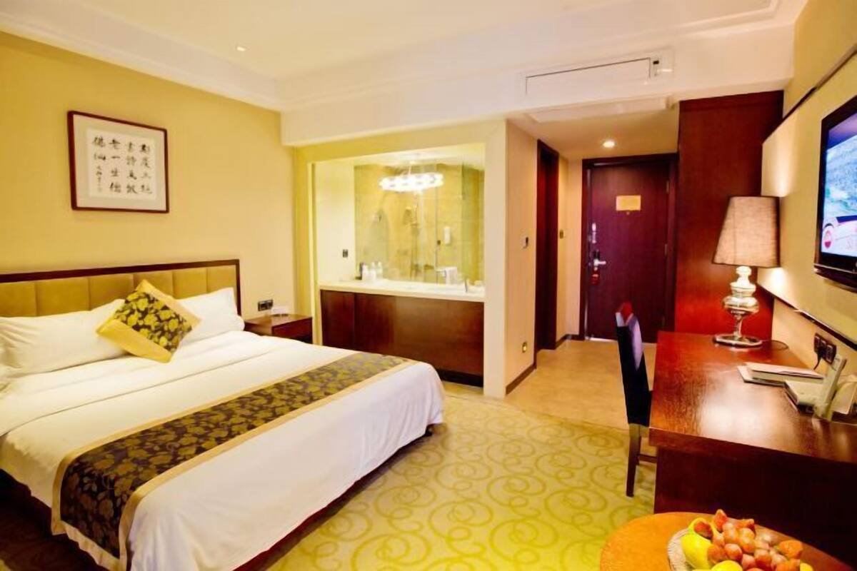 A hotel room with a bed, a desk, a television, and a mirror.
