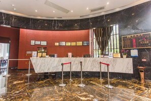 A reception area with a marble counter, red barriers, and a black and gold marble floor. - Minsheng Hotel (Yichang)