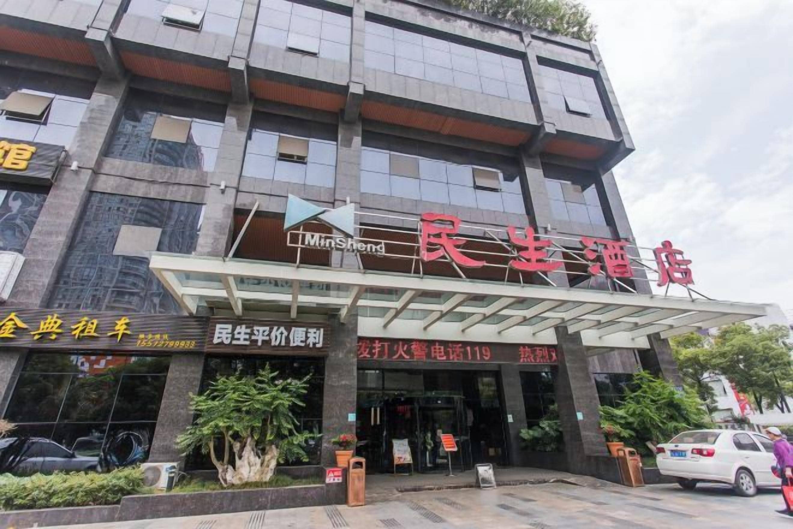 A hotel with a modern facade, a covered entrance, and a signboard with Chinese characters.