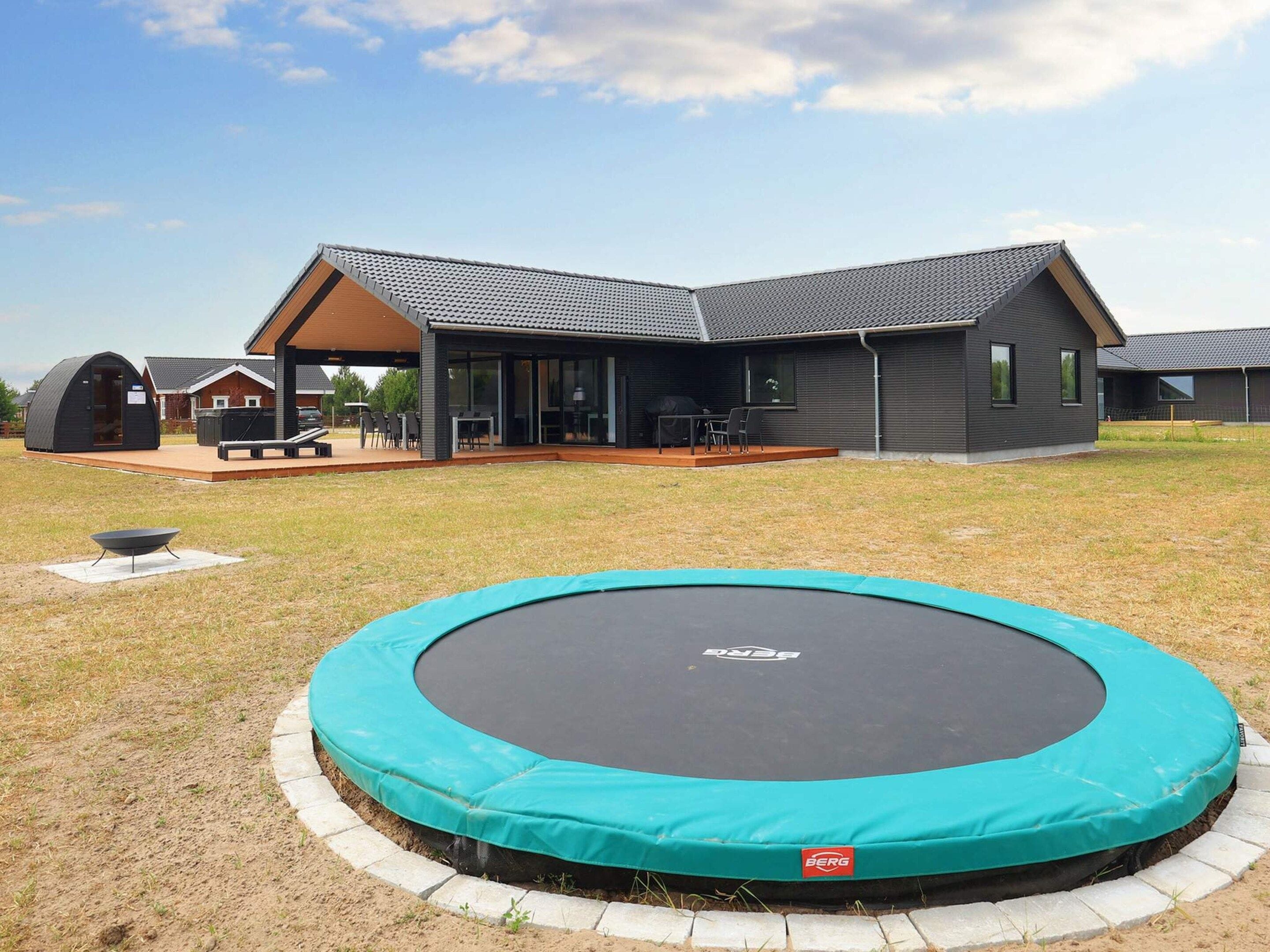 A residential property with a covered patio, a trampoline, and a house with a sloped roof.