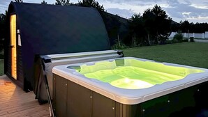 An outdoor hot tub on a wooden deck with a covered area to the left. - 5 Star Holiday Home in Vaeggerlose (Vaeggerlose)