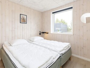 A bedroom with a bed, a window, and a wall-mounted light fixture. - 5 Star Holiday Home in Vaeggerlose (Vaeggerlose)