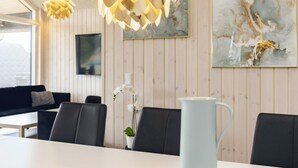 A modern dining area with a white table, black chairs, and a light blue pitcher. - 5 Star Holiday Home in Vaeggerlose (Vaeggerlose)