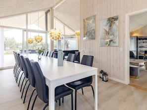 A modern dining area with a long table, black chairs, and decorative yellow pendant lights.
