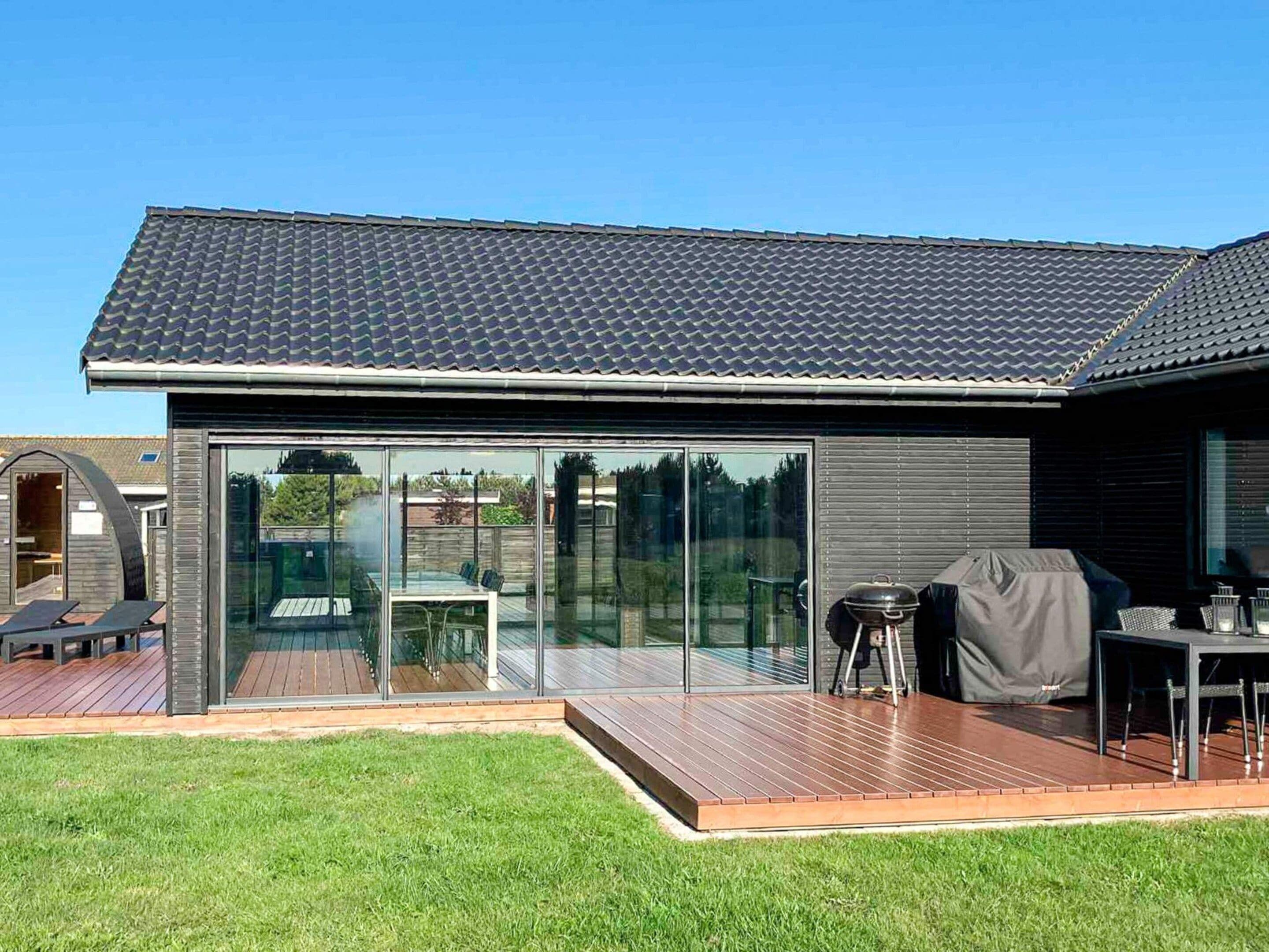 A modern house with a large glass door, a deck, and a barbecue area.