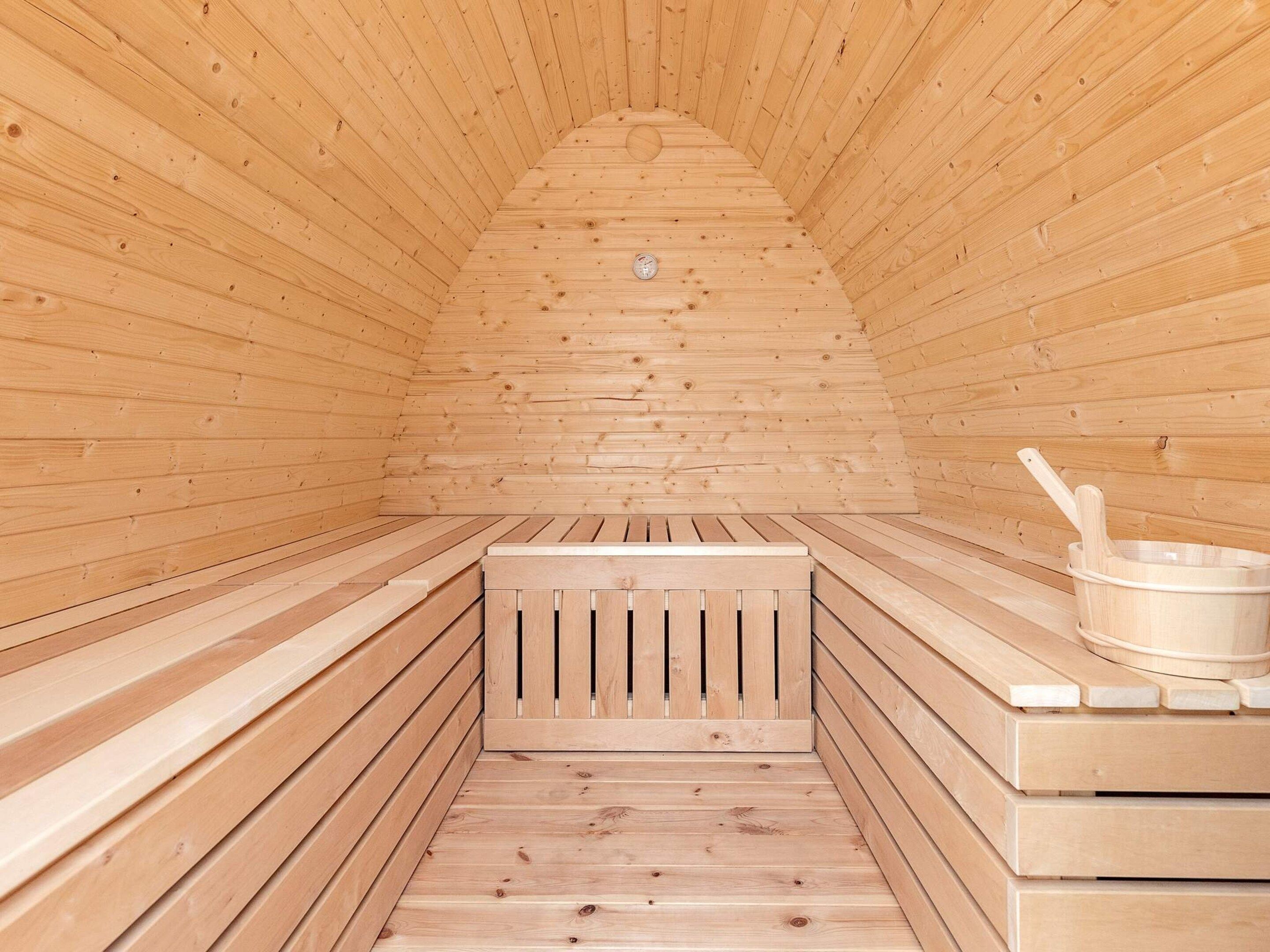 A sauna with wooden benches and a bench seat, a wooden wall, and a wooden floor.