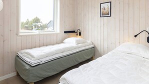A bedroom with two single beds, a window with a view of the outside, and a wall-mounted lamp. - 5 Star Holiday Home in Vaeggerlose (Vaeggerlose)