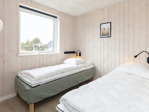 A bedroom with two single beds, a window with a view of the outside, and a wall-mounted lamp. - 5 Star Holiday Home in Vaeggerlose (Vaeggerlose)
