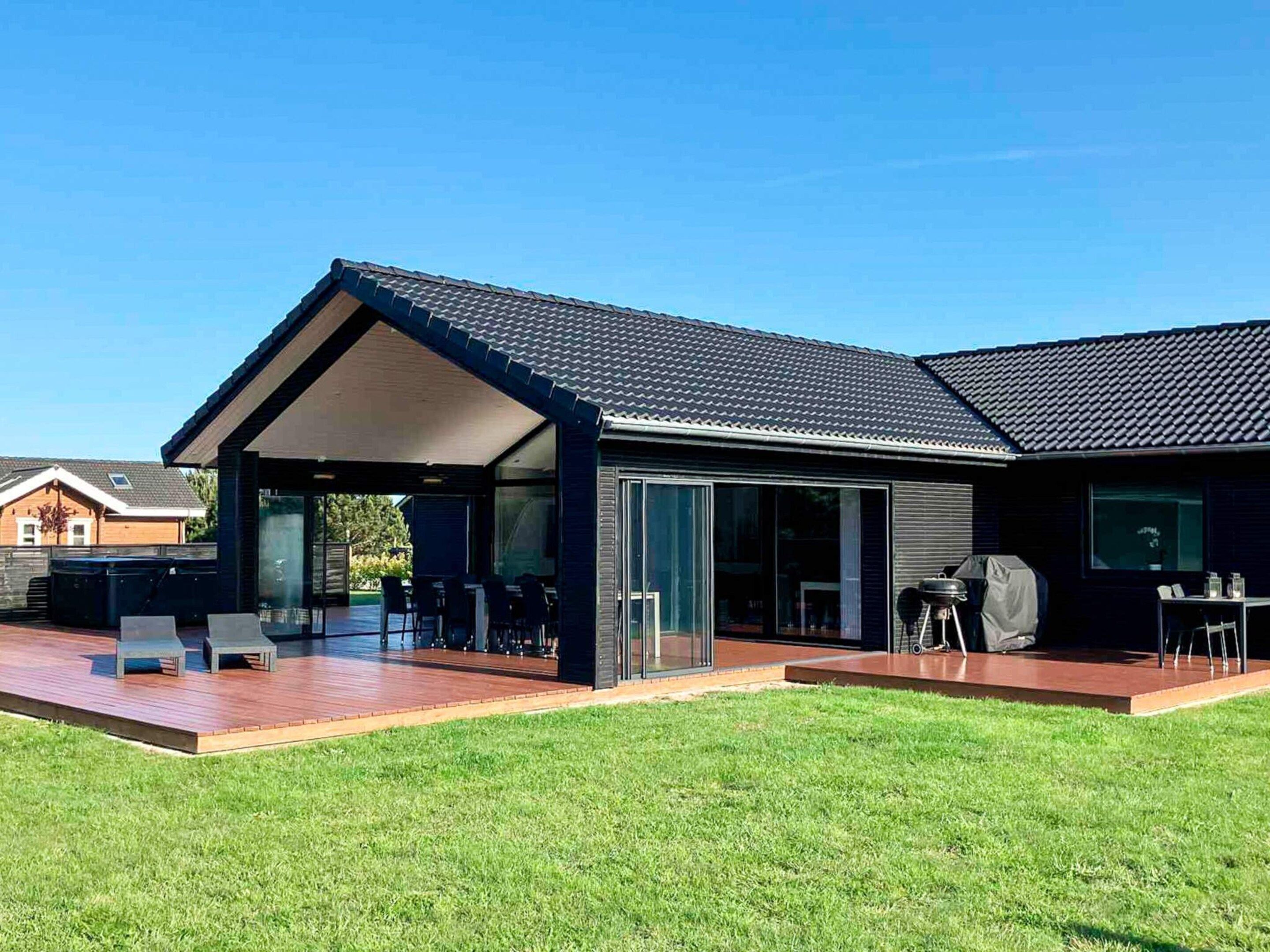 A modern house with a covered patio, a barbecue area, and a well-maintained lawn.
