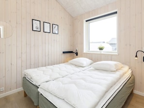 A bedroom with a bed, a window, and a wall-mounted light fixture.