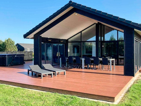A modern house with a deck, glass doors, and outdoor furniture.