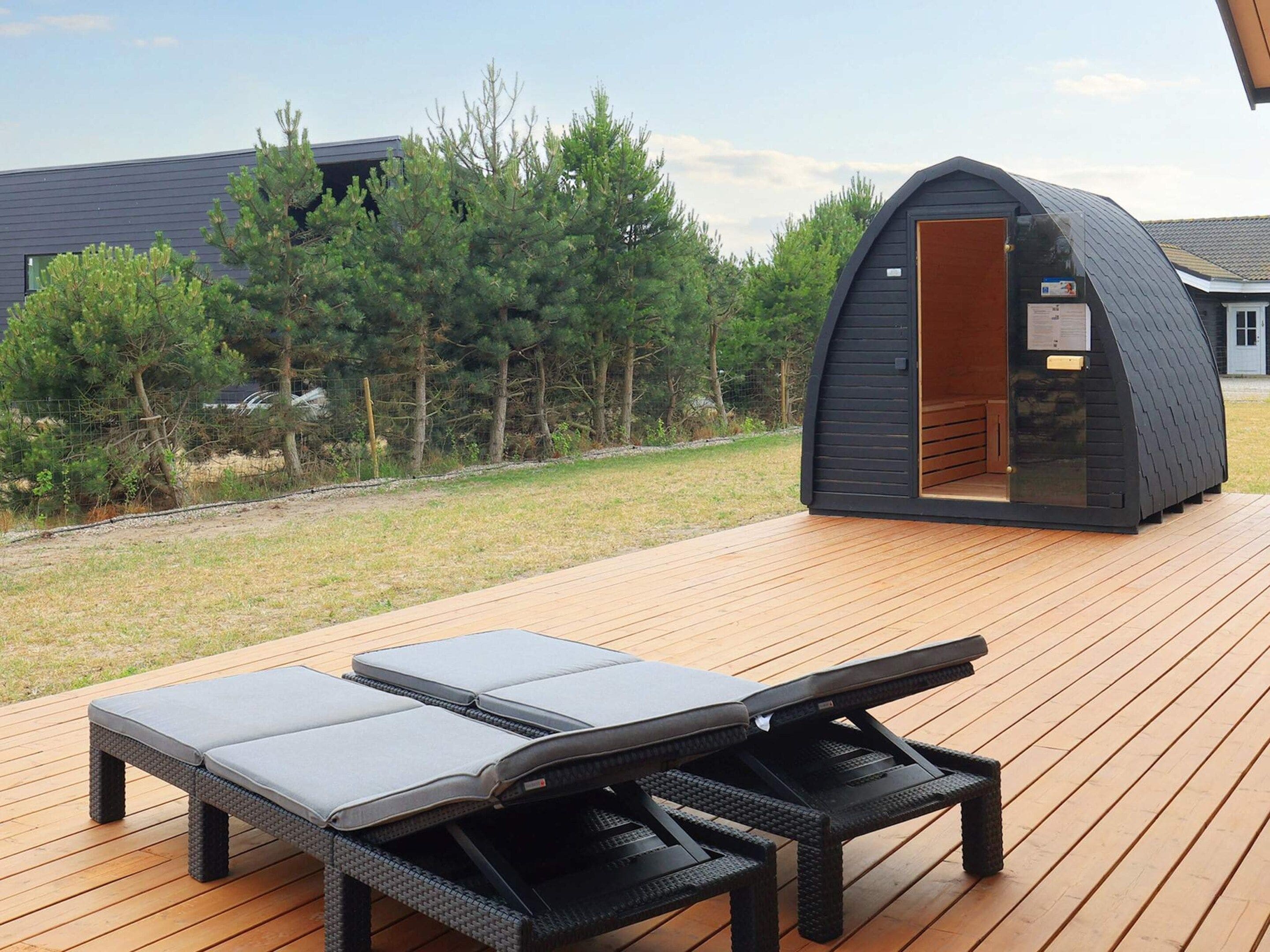 A deck with two lounge chairs and a small building with a door.