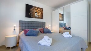 A modern bedroom with a large bed, a mirror, and a painting of a lion on the wall. - Gusto Comfortable Holiday Residence (Vodnjan)