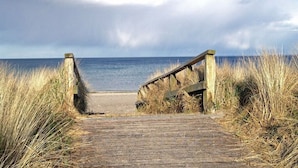 A wooden boardwalk leading to a beach with overcast skies. - Holiday Home by the Baltic Sea (Zingst)