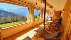 A sunlit room with wooden furniture, large windows, and a view of mountains. - Biologische Pension & Boerderij "de Veitenhof" (Umhausen)