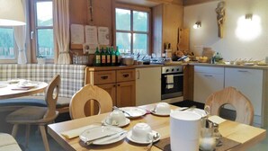 A cozy kitchen with wooden cabinets, a dining table set for four, and a window overlooking a scenic view. - Biologische Pension & Boerderij "de Veitenhof" (Umhausen)