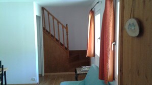 Una habitación con escalera de madera, cama con colcha azul turquesa y puerta de madera con adorno circular.
