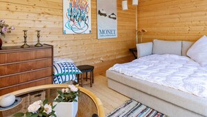 A wooden room with a bed, a dresser, a chair, and a wall with two posters. - 3 Person Holiday Home in Karrebaeksminde (Karrebæksminde)