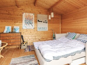 A cozy wooden room with a bed, a dresser, and artwork on the walls. - 3 Person Holiday Home in Karrebaeksminde (Karrebæksminde)