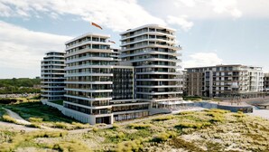 A modern multi-story residential building with balconies, a landscaped area in front, and a clear sky. - Apartment in Nieuwpoort by the Beach (Nieuwpoort)