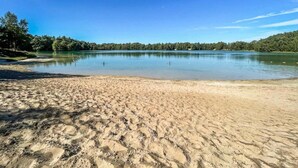 A sandy beach with a calm lake and a forested shoreline. - Chalet in Dutch Park With Garden and Terrace (Hoogersmilde)