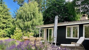 Una casa con terraza, mobiliario exterior y un jardín con lavanda.