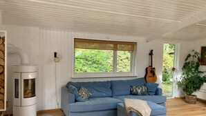 Una sala de estar acogedora con un sofá seccional azul, una estufa de leña y una guitarra.