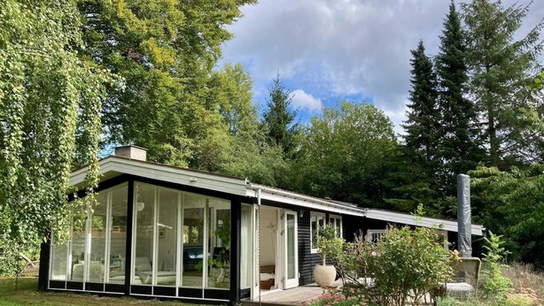 Una casa moderna con amplios ventanales, una terraza y una chimenea.