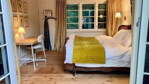 Un dormitorio con una cama, un escritorio con silla, una ventana con cortinas y una lámpara.