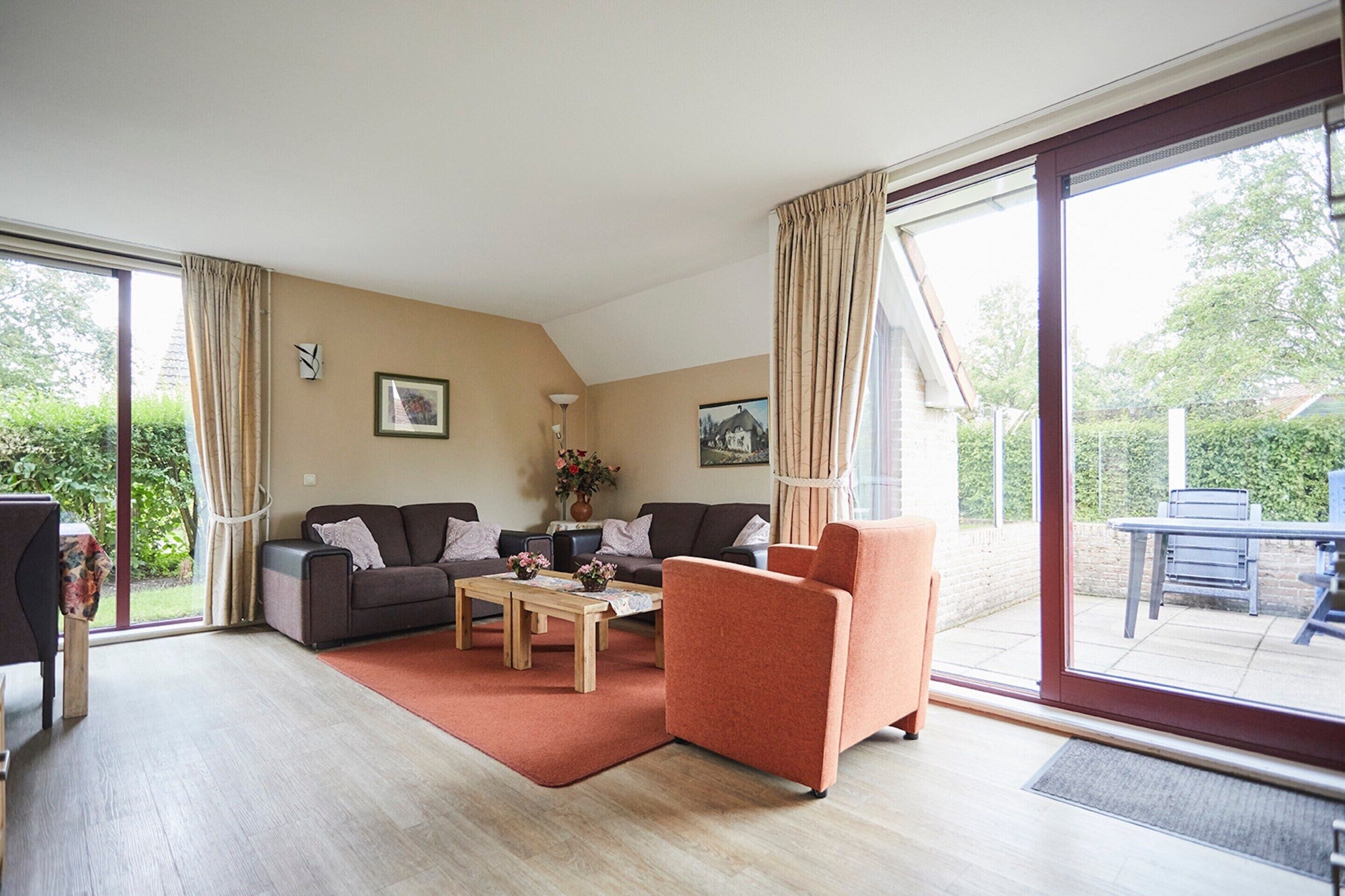 A spacious living room with a sofa, armchair, and coffee table, large sliding glass doors leading to a patio area.