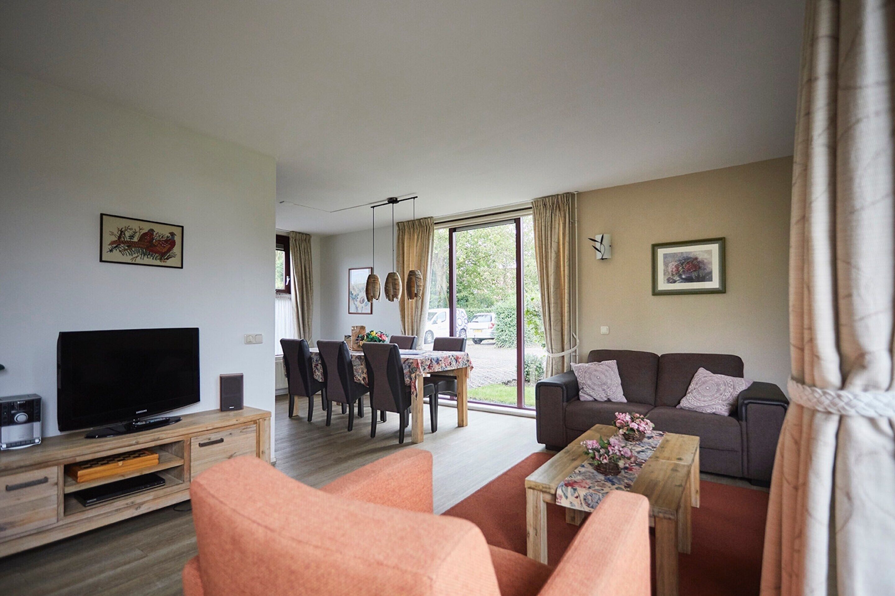A living room with a TV, sofa, and dining area.
