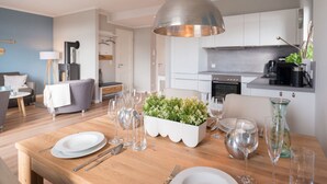 A modern kitchen with white cabinets, a built-in oven, and a hanging light fixture. - Holiday Apartment 11deg East (Heiligenhafen)