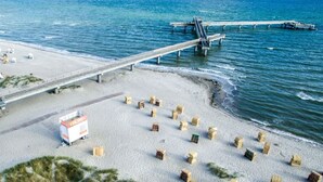 A beach with a pier and a lifeguard station. - Holiday Apartment 11deg East (Heiligenhafen)