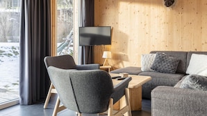 Una habitación acogedora con detalles de madera, una cabeza de animal montada en la pared, un televisor de pantalla plana y un sofá con cojines.