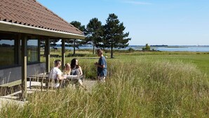 Un espace extérieur abrité, aménagé avec des sièges, et offrant une vue sur un lac et des arbres.